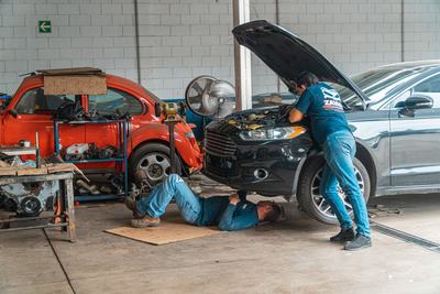 Two mechanics working on cars together in a workshop