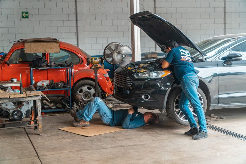 Two mechanics working on cars together in a workshop