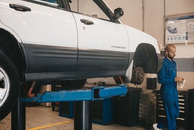 Subaru raised on a lift with a mechanic working behind it