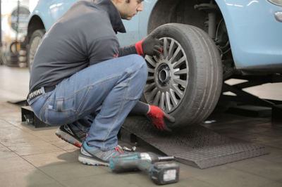 Mechanic crouched on the shop floor changing a wheel